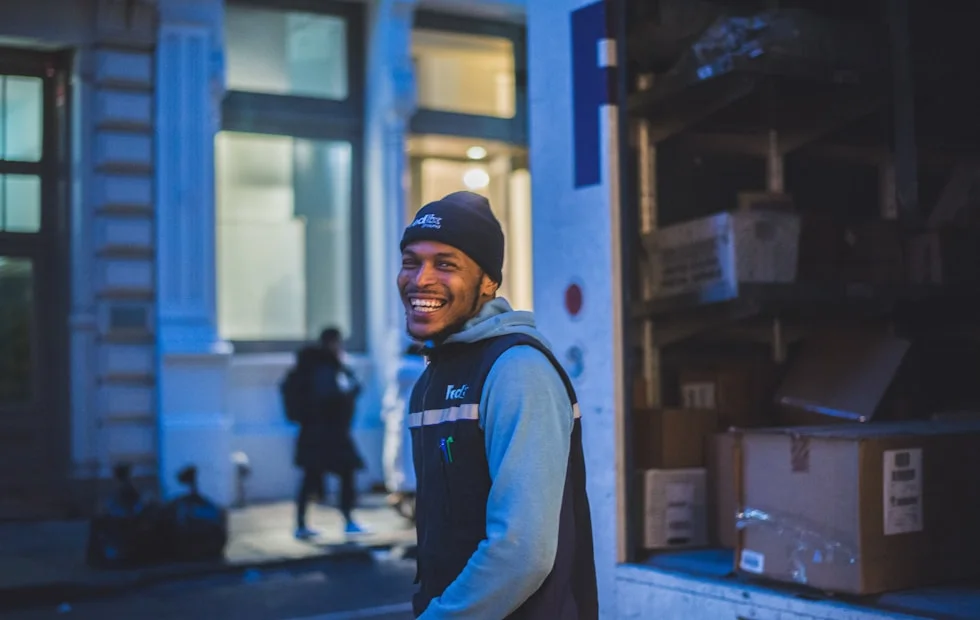 A smiling courier handing over a parcel from the UAE